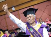 Seorang pria lansia tampak bersemangat mengikuti acara wisuda.