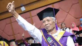 Seorang pria lansia tampak bersemangat mengikuti acara wisuda.