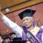 Seorang pria lansia tampak bersemangat mengikuti acara wisuda.