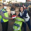 Polisi membagikan bendera merah putih kepada pengendara sepeda motor.