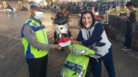 Polisi membagikan bendera merah putih kepada pengendara sepeda motor.