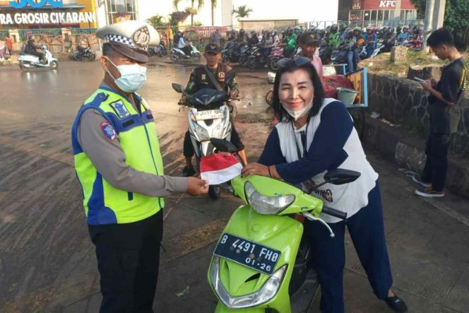 
					Polisi membagikan bendera merah putih kepada pengendara sepeda motor.
